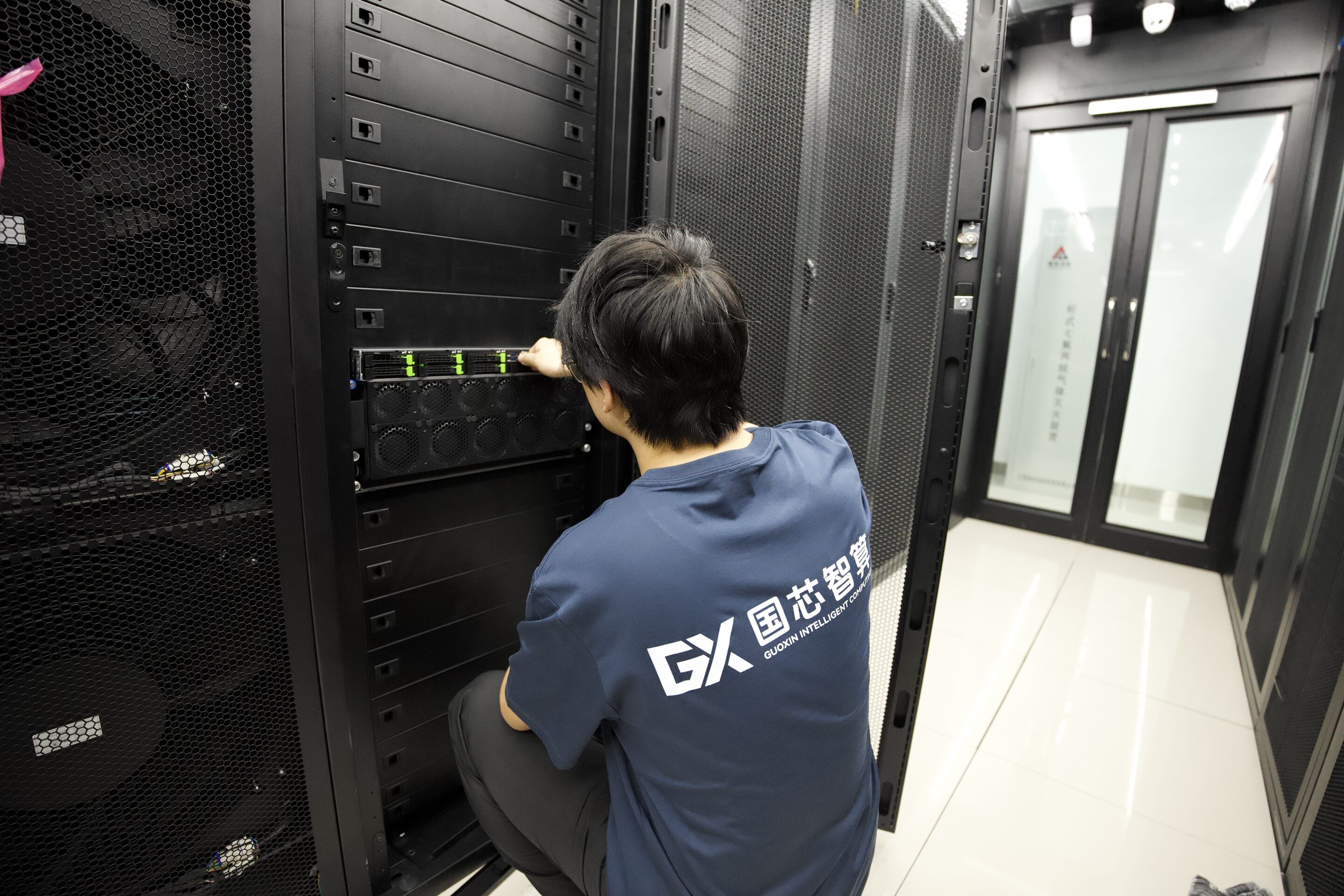 身穿印有 GX 标志工服的工程师在打开的机柜前操作